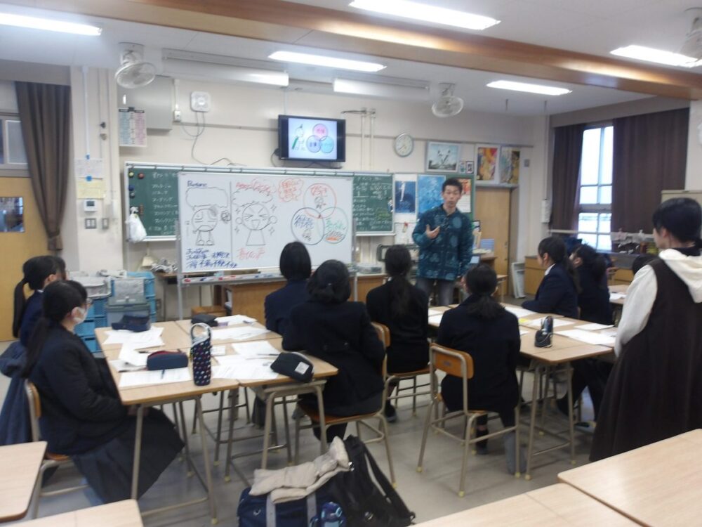 教室で、講師がホワイトボードに描いた棒人間を使って、生徒に話している様子